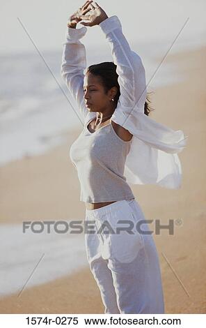 Side profile of a young woman stretching at the beach View Large Photo Image Stock Photography - Side profile of a young woman stretching at the beach. Fotosearch