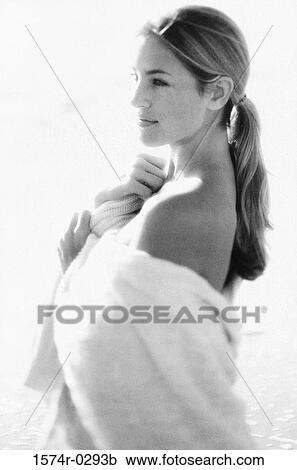 Stock Image - Side profile of a young woman wrapped in a towel on the beach. Fotosearch