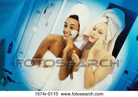 Two women wrapped in towels applying lotion View Large Photo Image Stock Image - Two women wrapped in towels applying lotion. Fotosearch