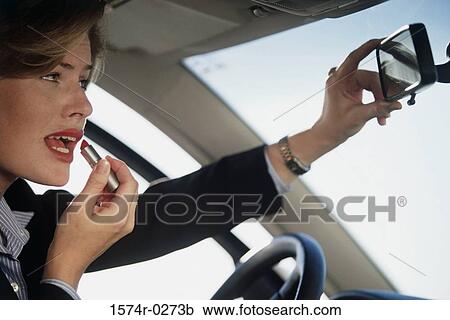 Woman applying lipstick in the rear view mirror of a car View Large Photo Image Stock Image - Woman applying lipstick in the rear view mirror of a car. Fotosearch