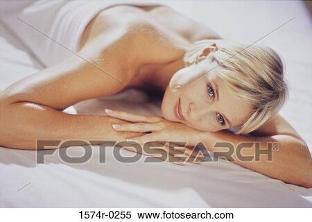 Stock Photography - Woman lying on a bed smiling. Fotosearch