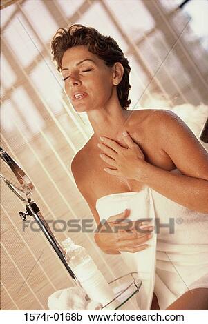 Woman standing with a towel wrapped around her View Large Photo Image Stock Image - Woman standing with a towel wrapped around her. Fotosearch