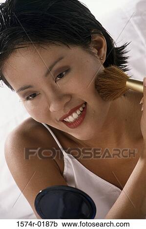 Stock Image - Young woman applying blush. Fotosearch