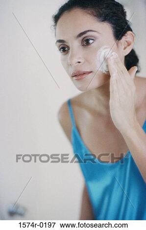 Young woman applying moisturizer on her cheek View Large Photo Image Stock Photo - Young woman applying moisturizer on her cheek. Fotosearch