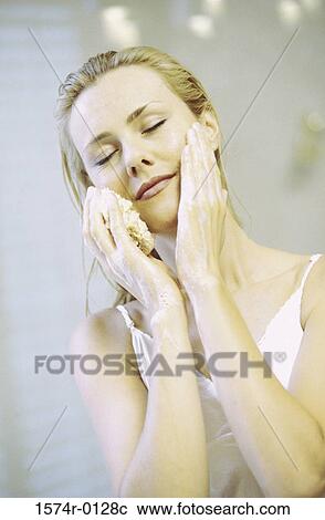 Young woman cleaning her face with a sponge View Large Photo Image Stock Image - Young woman cleaning her face with a sponge. Fotosearch