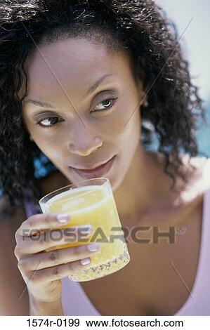 Stock Photo - Young woman drinking orange juice. Fotosearch