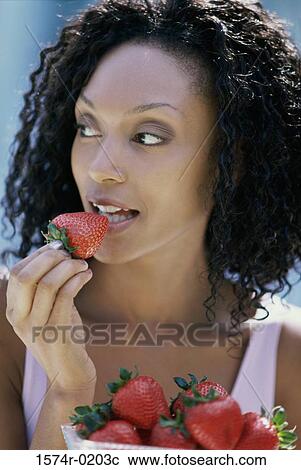 Young woman eating a strawberry View Large Photo Image Stock Image - Young woman eating a strawberry. Fotosearch