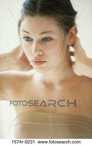 Stock Image - Young woman standing with her hands on the back of her neck. Fotosearch
