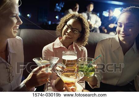 Stock Image - Close-up of three young women toasting with glasses. Fotosearch