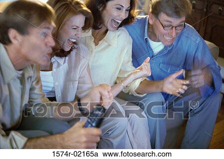 Close-up of two mid adult couples watching television View Large Photo Image Stock Image - Close-up of two mid adult couples watching television. Fotosearch