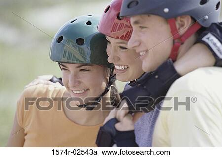 Stock Image - Close-up of two teenage girls and a teenage boy wearing helmets. Fotosearch