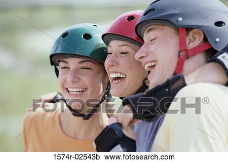 Stock Image - Close-up of two teenage girls and a teenage boy wearing helmets. Fotosearch