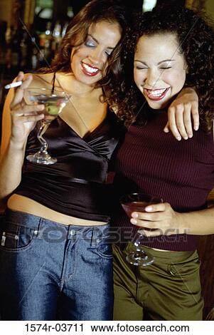 Close-up of two young women standing in a bar View Large Photo Image Stock Image - Close-up of two young women standing in a bar. Fotosearch