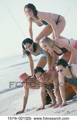 Stock Image - Group of young people making a human pyramid on the beach. Fotosearch