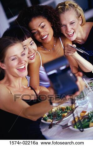 Stock Image - High angle view of a group of young women taking a photograph of themselves. Fotosearch