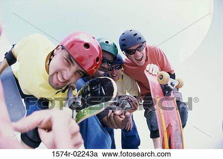 Stock Image - Low angle view of a group of young men holding skateboards. Fotosearch
