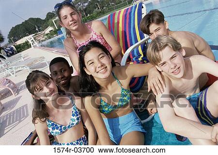 Stock Image - Portrait of a group of teenagers sitting beside a swimming pool. Fotosearch