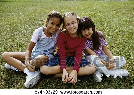 Portrait of three girls sitting on a lawn View Large Photo Image Stock Photo - Portrait of three girls sitting on a lawn. Fotosearch