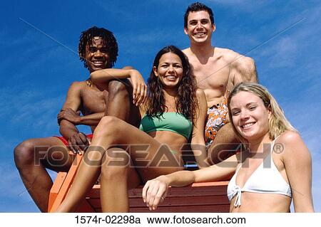 Stock Image - Portrait of two teenage couples sitting on a lifeguard tower. Fotosearch