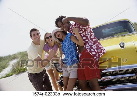 Stock Image - Portrait of two teenage couples standing beside a car. Fotosearch