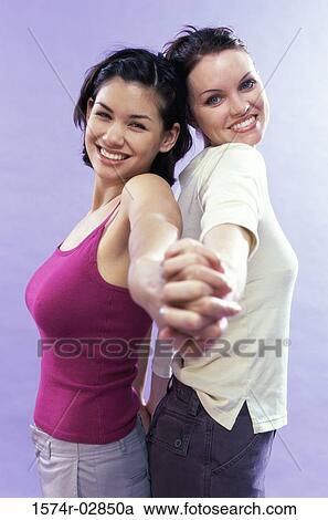 Portrait of two young women standing back to back View Large Photo Image Stock Image - Portrait of two young women standing back to back. Fotosearch
