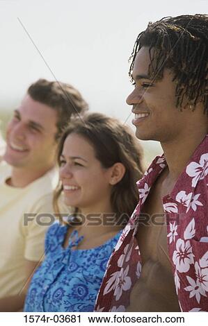 Stock Image - Side profile of two teenage boys and a teenage girl smiling. Fotosearch