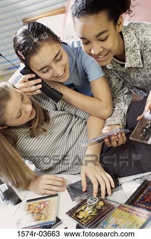 Three teenage girls looking at CDs while talking on a cordless phone View Large Photo Image Stock Image - Three teenage girls looking at CDs while talking on a cordless phone. Fotosearch
