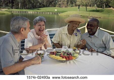 Stock Image - Two senior couples sitting at an outdoor restaurant. Fotosearch