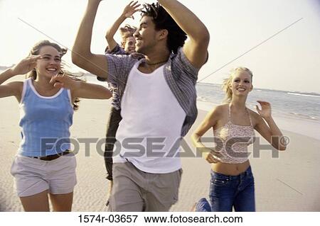 Stock Photo - Two teenage couples playing football on the beach. Fotosearch