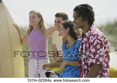 Stock Image - Two teenage couples standing beside a car. Fotosearch