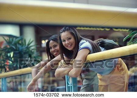 Stock Image - Two teenage girls leaning over a railing. Fotosearch