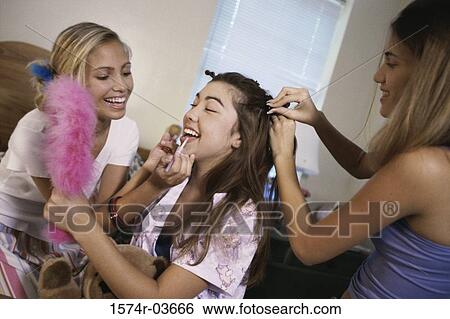 Stock Photograph - Two teenage girls styling their friend's hair. Fotosearch