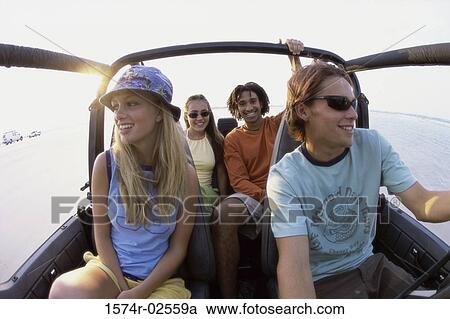 Stock Image - Two young couples sitting in a jeep. Fotosearch