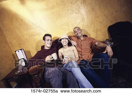 Two young men and a young woman sitting in a cafe drinking coffee View Large Photo Image Stock Image - Two young men and a young woman sitting in a cafe drinking coffee. Fotosearch