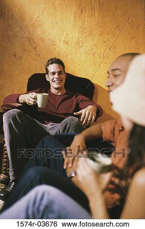 Two young men and a young woman sitting in a cafe drinking coffee View Large Photo Image Stock Photograph - Two young men and a young woman sitting in a cafe drinking coffee. Fotosearch