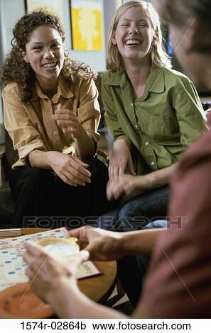 Stock Image - Two young women and a young man playing scrabble. Fotosearch