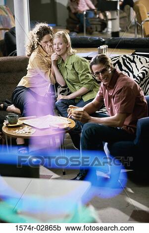 Stock Image - Two young women and a young man sitting in a cafeteria playing scrabble. Fotosearch