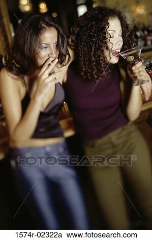 Stock Image - Two young women drinking in a bar. Fotosearch