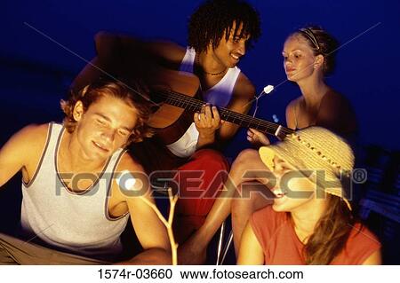 Young couple roasting marshmallows on the beach View Large Photo Image Stock Image - Young couple roasting marshmallows on the beach. Fotosearch
