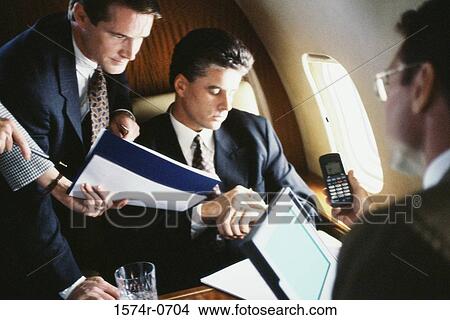 Picture - Business executives discussing in a commercial airplane. Fotosearch