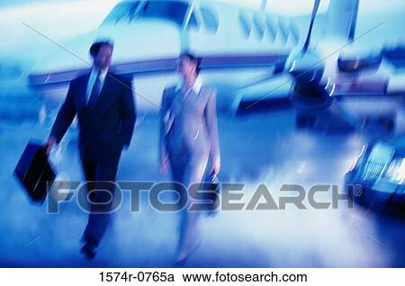 Stock Image - Businessman and a businesswomen walking with briefcases. Fotosearch