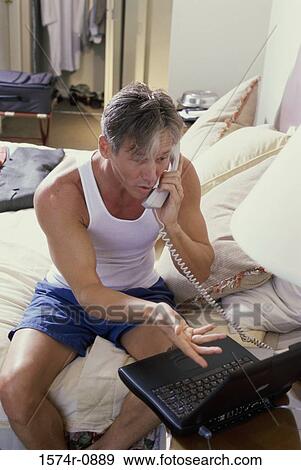 Stock Photo - Businessman in a hotel room talking on the telephone. Fotosearch