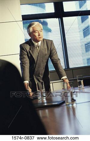 Stock Photo - Businessman leaning against a table in a meeting. Fotosearch