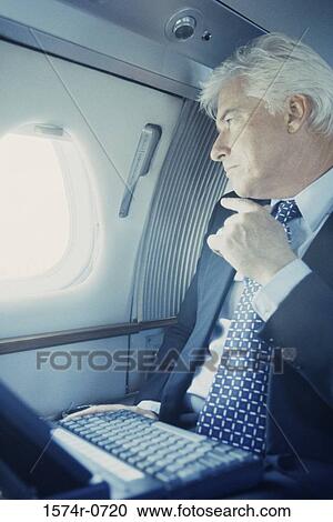 Businessman looking out of a window in an airplane View Large Photo Image Stock Image - Businessman looking out of a window in an airplane. Fotosearch