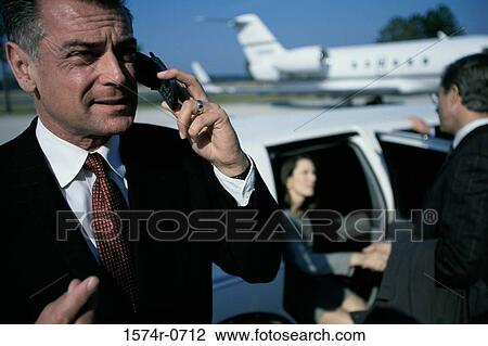 Businessman talking on a mobile phone at the airport View Large Photo Image Stock Image - Businessman talking on a mobile phone at the airport. Fotosearch