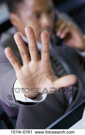 Stock Image - Businessman talking on a telephone and holding his hand out. Fotosearch