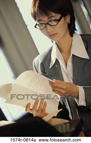 Stock Image - Businesswoman seated behind a desk in an office. Fotosearch