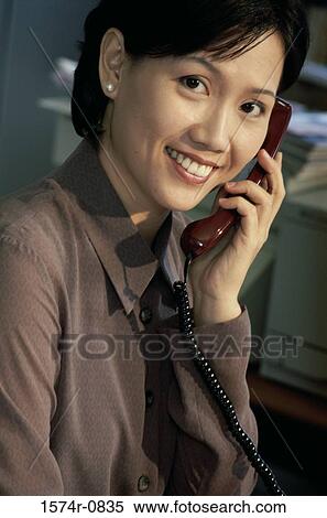 Businesswoman talking on a landline telephone View Large Photo Image Stock Photography - Businesswoman talking on a landline telephone. Fotosearch
