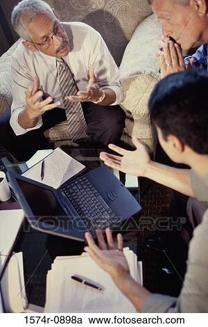Stock Image - High angle view of business executives discussing in an office. Fotosearch