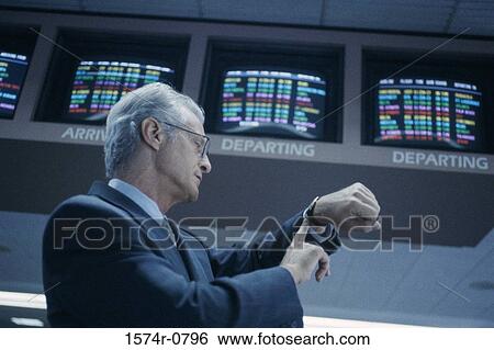 Low angle view of a businessman looking at his wrist watch View Large Photo Image Stock Photograph - Low angle view of a businessman looking at his wrist watch. Fotosearch